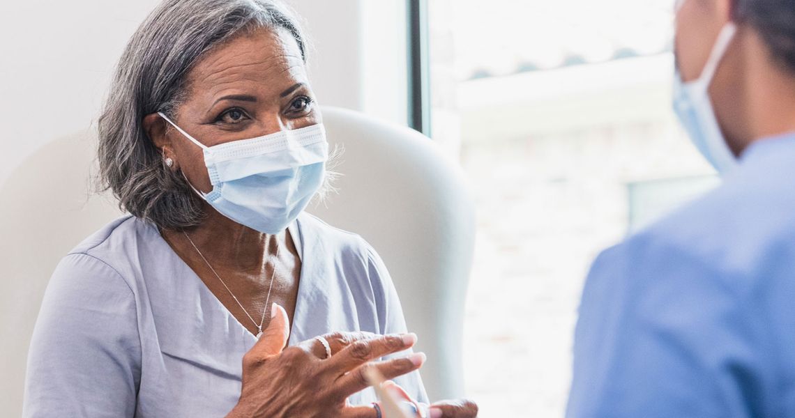 female patient wearing mask and speaking with doctor